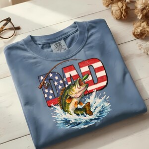 Father's Day and 4th of July fishing shirt design featuring a bold American flag bass fishing DAD graphic, shown as an instant digital download PNG for sublimation, DTF, and Cricut projects