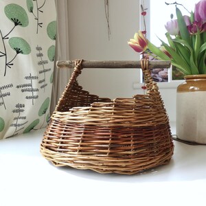A Small Round Handmade Willow Basket with a Wooden Handle