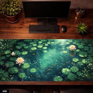Pode incluir: Um tapete de mesa retangular com uma serena cena de lagoa com nenúfares, flores de lótus e peixes pequenos. O design do tapete incorpora tons de verde e azul, criando uma estética tranquila. O tapete está em uma mesa de madeira com teclado, mouse e monitor.