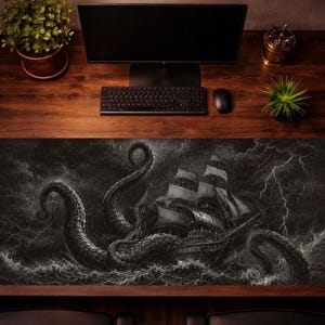 May include: A rectangular desk mat featuring a monochromatic illustration of a large sailing ship being attacked by a giant octopus amidst a stormy sea with lightning strikes. The mat is positioned on a wooden desk with a computer monitor and keyboard.