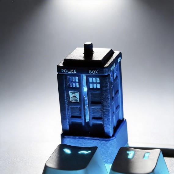 A tiny hand-cast resin telephone booth that replaces your Escape key — miniature diorama-level craft sitting right on your keyboard.