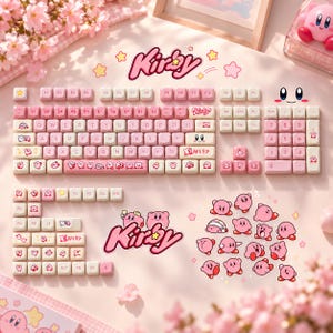 May include: A mechanical keyboard keycap set featuring a pink and cream color scheme with Kirby character graphics. The set includes a full QWERTY layout, a number pad, function keys, and various decorative keys with Kirby illustrations and logos.