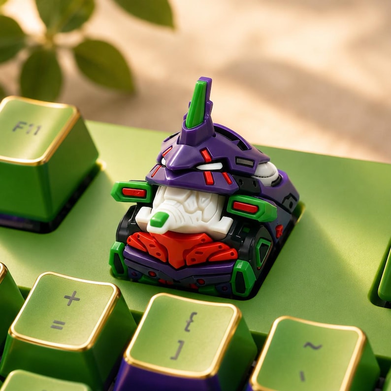 May include: A mechanical keyboard keycap featuring a stylized purple, green, and white robot head design with red accents. The keycap is mounted on a green keyboard base with other green keys visible, including one marked with the text F11.