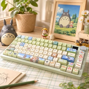 May include: A mechanical keyboard with a light green frame and custom keycaps featuring various animated character illustrations, including a space bar with a detailed landscape scene, a silver rotary knob, and light-colored keys with black letters.