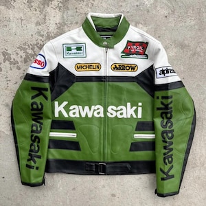 Può includere: Giacca da moto Kawasaki verde, bianca e nera con diverse toppe e il logo Kawasaki. La giacca ha una chiusura a zip, un colletto e una cintura in vita. Le maniche presentano il nome Kawasaki stampato verticalmente.