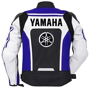 Op de afbeelding: Motorjas in zwart, wit en blauw. De achterkant toont het woord "YAMAHA" in wit boven een Yamaha-logo. De jas heeft witte mouwen en blauwe details, met een klassieke biker-esthetiek.