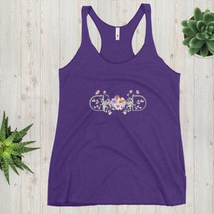 May include: A purple racerback tank top with a floral design. The design features the word "DAD" in a stylized font, surrounded by a floral arrangement with pink, peach, and purple flowers. The tank top is made of a soft material.