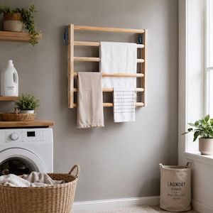 May include: A wall-mounted wooden towel rack with horizontal rungs, featuring a large white towel, a beige towel, and a smaller white towel with thin horizontal stripes draped over the bars. The rack is constructed from light-toned wood.