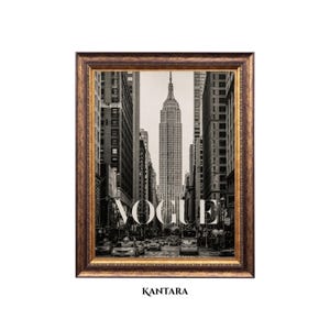 May include: A framed black and white photograph of a New York City street scene featuring the Empire State Building centered in the distance. The word VOGUE is printed in large white capital letters over the image. The frame is ornate and dark gold.