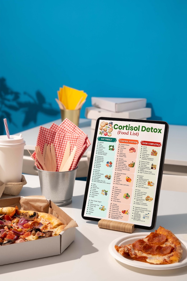 May include: A tablet displays a "Cortisol Detox (Food List)" with food categories. A pizza in a box, a slice of pizza, and a drink with a straw are on a white table. Napkins and utensils are in a metal bucket. A blue background completes the scene.