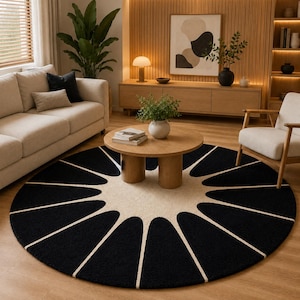 May include: A large circular area rug featuring a bold, high-contrast pattern of black, petal-like shapes radiating outward from a solid cream-colored center, creating a sunburst effect across the floor surface.