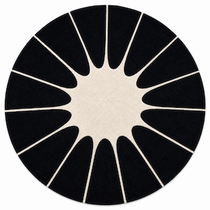 May include: A circular area rug featuring a high-contrast design with a solid black background and a central cream-colored starburst pattern. The cream shape extends outward with twelve pointed rays that reach toward the edge of the rug.