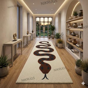 Peut inclure: Un tapis rectangulaire crème avec un motif de serpent marron et bleu marine. Le corps du serpent est un motif sinueux, et la tête est en bas du tapis. Le tapis est dans un couloir avec un sol en bois et des murs blancs.