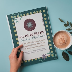 May include: A book titled "GLOW & FLOW Overwhelmed Mom Routine" with a floral design and a cup of coffee on a light blue surface. The book's cover has a dark green border with a floral design and the text "GLOW & FLOW Overwhelmed Mom Routine".