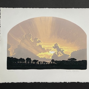 Könnte beinhalten: Ein Holzschnitt, der einen Sonnenuntergang mit goldenem Himmel und Wolken zeigt. Der Druck ist mit "Radiant" betitelt und mit 1/19 nummeriert. Die Unterschrift des Künstlers, "Caley Armstrong", befindet sich in der unteren rechten Ecke.