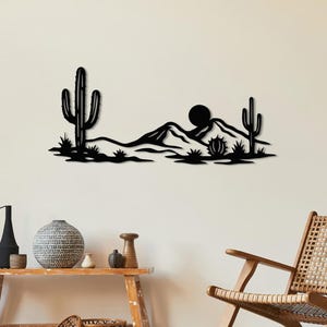May include: Black metal wall art depicting a desert landscape with cacti, mountains, and a sun. The artwork is mounted on a white wall above a wooden bench with decorative items and a woven chair. The scene evokes a Southwestern theme.