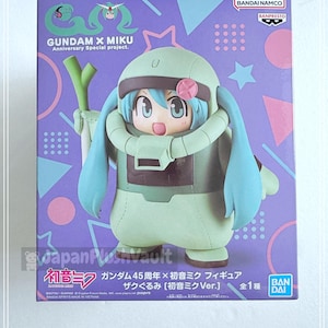 May include: A boxed Gundam x Miku anniversary special project figure. The figure is a stylized character in a green and brown outfit with blue hair. The box is purple with pink and blue geometric shapes and the text "GUNDAM X MIKU".