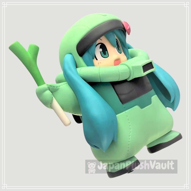 May include: A figurine of a cartoon character in a green and teal outfit, holding a green vegetable. The character has teal hair, large eyes, and a pink flower. The figure is in a dynamic pose, with a light gray background.