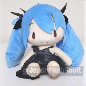 May include: A plush doll with a light blue wig and long pigtails. The doll has a white face with brown eyes and rosy cheeks. It is wearing a black dress with a bow and black hair accessories. The doll is sitting.