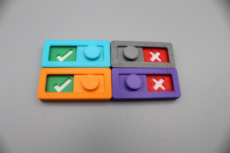 May include: Four colorful plastic toggles with a checkmark or an X on one side and a round button on the other. The toggles are blue, orange, gray, and purple.