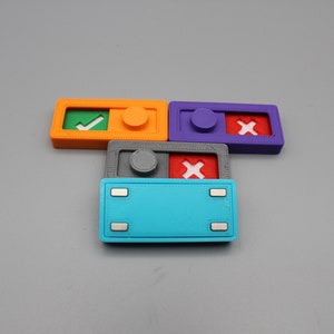 May include: Four small plastic toggle switches with different colored bases and symbols. The switches are orange, purple, gray, and blue. The symbols are a green checkmark, a red X, a white X, and a blank space.