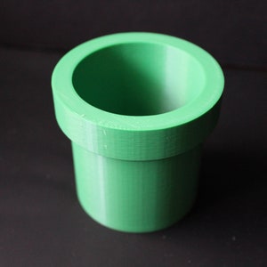May include: A green plastic pipe-shaped planter, resembling a video game item.