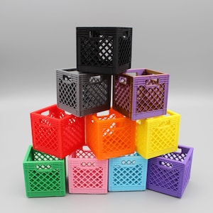 May include: A collection of colorful, small plastic milk crates stacked in a pyramid shape. The crates are in various colors, including red, orange, yellow, green, blue, pink, purple, gray, and black. The crates have a lattice design.