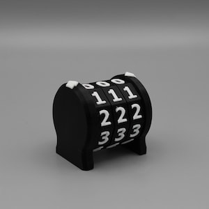 May include: A black mechanical counter with three rotating wheels featuring white raised numbers. Each wheel displays the digits zero through three in a vertical sequence. The device has a curved top and a stable base, constructed from matte black material.