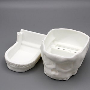May include: White plastic skull-shaped box with a removable lid. The box has a small compartment inside with a divider for holding small items.