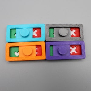 May include: Four colorful plastic puzzle pieces with a sliding mechanism. Each piece has a different color: blue, orange, gray, and purple. Each piece has a green, red, and white design.