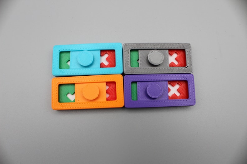 May include: Four colorful plastic puzzle pieces with a sliding mechanism. Each piece has a different color: blue, orange, gray, and purple. Each piece has a green, red, and white design.