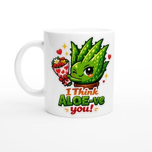 以下が含まれることがあります： 白いセラミックマグカップ。漫画のアロエベラ植物が花のブーケを持っています。緑色のアロエベラは笑顔で、マグカップには「I Think ALOE-ve you！」の文字が緑と黄色でプリントされています。