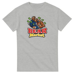 Puede incluir: Camiseta gris claro con un oso de dibujos animados con traje cayendo hacia atrás, rodeado de dinero. El texto "BEAR Market" está en rojo y amarillo. Es una prenda informal.