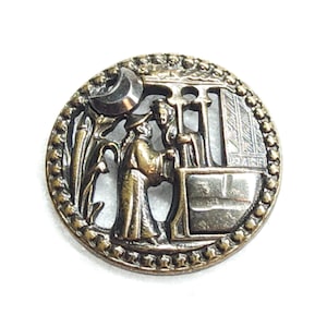 May include: Antique bronze-colored button with a detailed relief scene. The button features a circular design with a border of small beads. The central image depicts two figures in traditional attire, a crescent moon, and architectural elements.