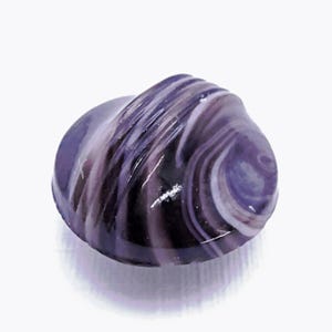 May include: A polished, rounded stone with a swirling pattern of purple, lavender, and white. The stone has a smooth, glossy surface and is set against a white background. The shape is reminiscent of a seashell.