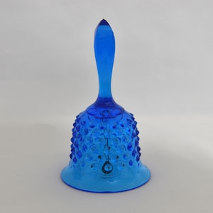 May include: A cobalt blue glass bell with a textured surface and a pointed handle.