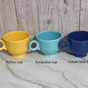 May include: Three ceramic mugs in different colors: yellow, turquoise, and cobalt blue. Each mug has a unique handle and a textured exterior.