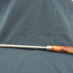 Puede incluir: Un afilador de cuchillos de acero plateado con un mango de plástico marrón y amarillo.