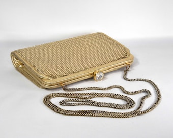 May include: A gold mesh clutch purse with a chain strap and a clear rhinestone clasp.