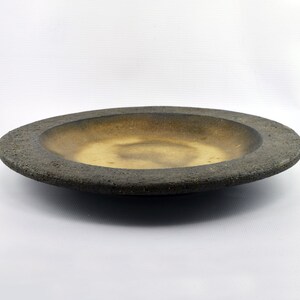 May include: A large, round, ceramic serving dish with a textured, dark brown rim and a smooth, light brown interior.