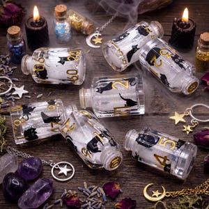May include: Small, clear glass bottles decorated with black cat designs and gold numerals. The bottles contain white glitter and are arranged on a wooden surface with candles, crystals, and dried flowers. A mystical theme.