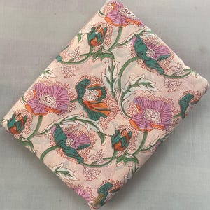 Könnte beinhalten: Gefalteter Stoff mit einem Blumenmuster mit rosa, orangefarbenen und türkisfarbenen Blumen auf hellrosa Hintergrund. Das Design umfasst grüne Stiele und Blätter und schafft ein botanisches Thema.