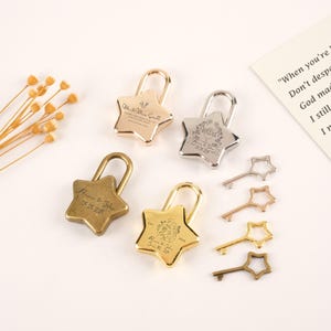 May include: Several star-shaped padlocks in gold, silver, and bronze, with star-shaped keys. The padlocks are engraved with names and dates, including "Mr. & Mrs. Small" and "Alicia & John 05.05.2025".