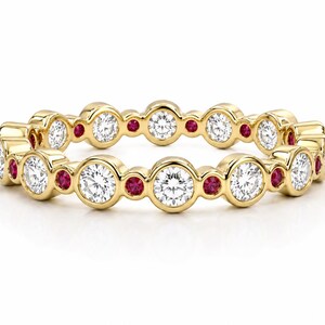 Puede incluir: Un anillo de oro con diamantes blancos redondos y pequeñas piedras rojas alternados. Las piedras preciosas están engastadas en biseles individuales, creando una banda continua. El anillo tiene un acabado pulido y un diseño clásico.