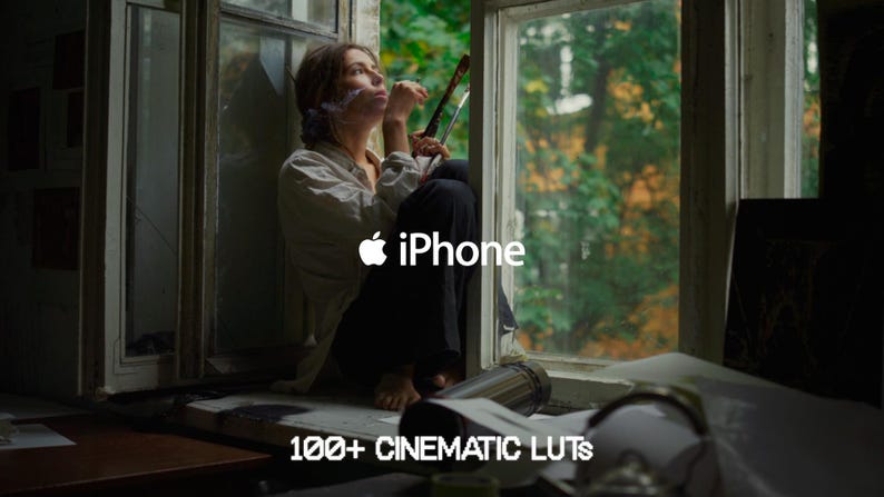 May include: A person sits in a window, holding art supplies. The image includes the Apple iPhone logo and the text "100+ CINEMATIC LUTS". The scene is set in a room with natural light and a view of trees outside the window.