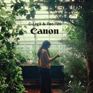May include: A person wearing a mustard yellow long-sleeved shirt and dark trousers stands in a greenhouse filled with lush green plants. The text C-Log3 & Rec.709 and Canon is printed in black in the centre of the image against the glass structure.