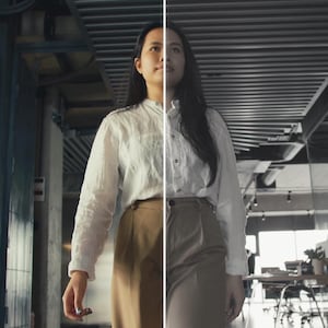 May include: A woman in a white button-down shirt and tan pants walks toward the camera in a modern office setting. A man in a white shirt and black pants is partially visible on the left. The image is split in half, with the right side in grayscale.