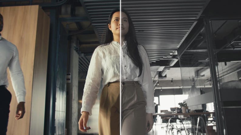 May include: A woman in a white button-down shirt and tan pants walks toward the camera in a modern office setting. A man in a white shirt and black pants is partially visible on the left. The image is split in half, with the right side in grayscale.