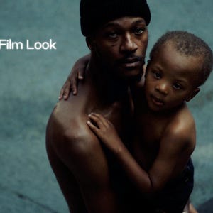 May include: A man in a black beanie embraces a child, both with dark skin. The image has a muted colour palette with the text "16mm Film Look" in the upper left corner. The background is a textured teal colour.