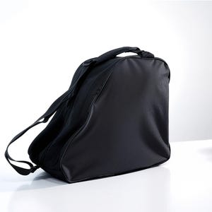 May include: Black ice skate bag with a shoulder strap and a top handle. The bag is made of a durable material and features a textured front panel. The bag is designed to carry ice skates and other accessories.